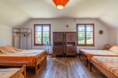 a room with two beds and a fan and windows at Chalet des Bruyères in Saint-Jorioz