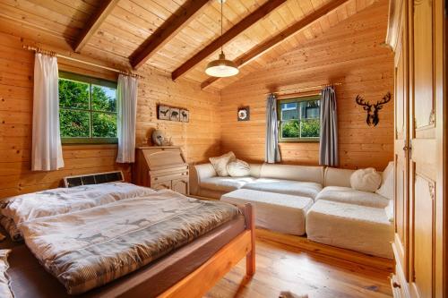 a bedroom in a log cabin with a bed and a couch at Pröllerhütte in Grün
