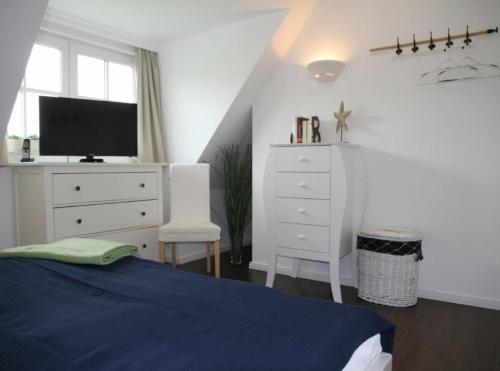a bedroom with a bed and a dresser with a tv at Villa Sorgenfrei in Zinnowitz