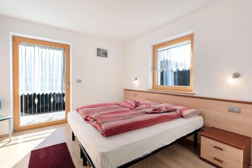 a bedroom with a bed and two windows at Innerjerberhof Sunnseit in Lauregno