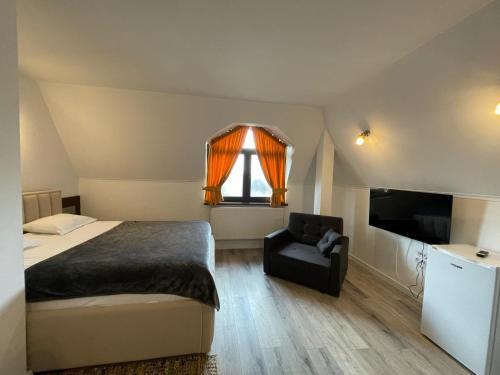 a bedroom with a bed and a chair and a television at Pensiunea Oficial in Prejmer