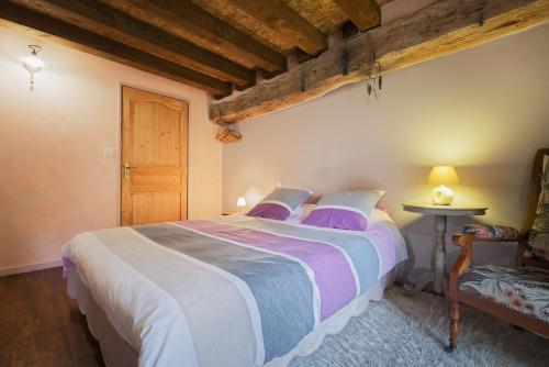 a bedroom with a large bed with purple pillows at Ker Cado - Chambre d'hôtes in Mauron
