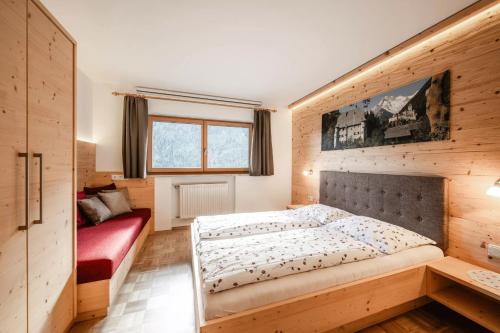 a bedroom with a large bed and a red couch at Rieplechn App in Sand in Taufers