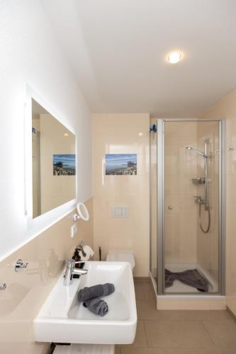 a white bathroom with a sink and a shower at Claudia's Seeherz in Wasserburg
