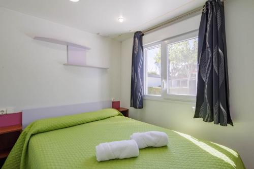 a bedroom with a green bed with two towels on it at Bungalow E in Pontevedra