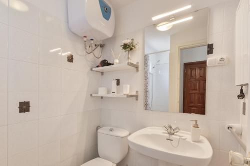 a white bathroom with a toilet and a sink at Casa Isabel in Santa Brígida