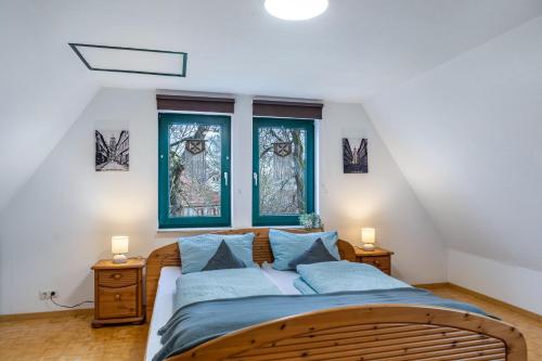a bedroom with a bed with blue sheets and two windows at Ferienwohnung Altstadtblick in Alsfeld