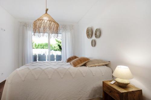 a white bedroom with a bed and a window at Luxury Boho Style Apartment Nazaré in Nazaré