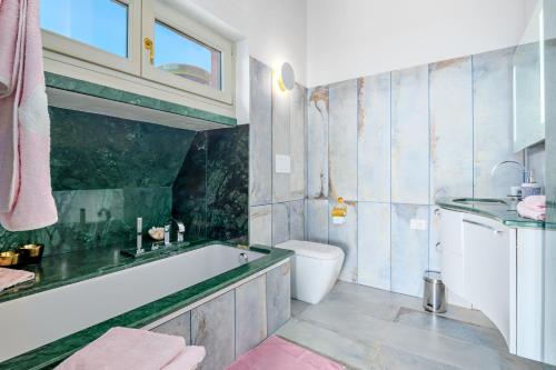 a bathroom with a tub and a toilet and a sink at Villa Maryna in Olbia