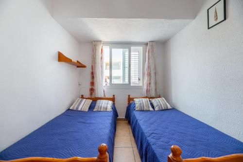 two beds in a small room with a window at Apartamento Trilo 24 in Es Pujols