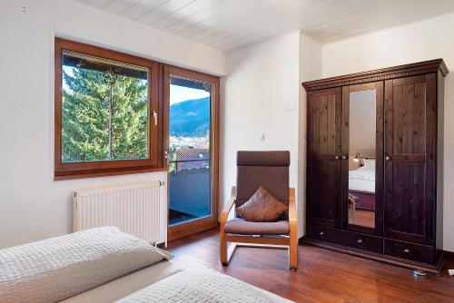 a bedroom with a bed and a chair and a window at Ferienwohnung Waldblick in Simonswald