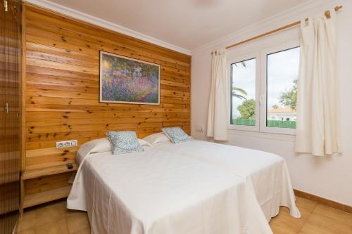 two beds in a bedroom with a wooden wall at 5ª Avenida in S'Algar