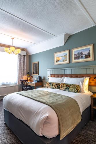 a bedroom with a large bed and a desk at The Swan Inn by Innkeeper's Collection in Horning