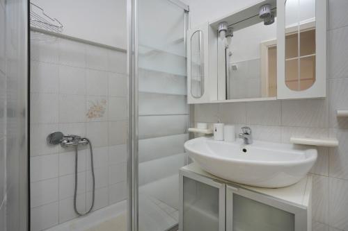a white bathroom with a sink and a shower at Casa Pà in Ostuni