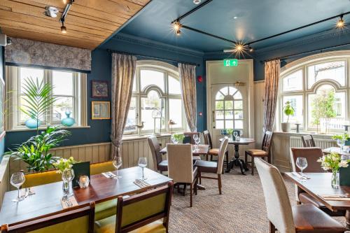 a restaurant with tables and chairs and windows at The Swan Inn by Innkeeper's Collection in Horning