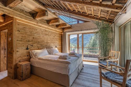 a bedroom with a bed and a large window at Dolomites Luxe Cesa Del Louf in Arabba