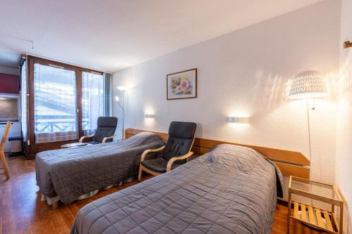 a hotel room with two beds and two chairs at Les cybeles - studio 3 personnes in Brides-les-Bains