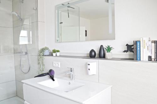 a white bathroom with a sink and a mirror at Hq16 - Modernes Ferienhaus in Neuenburg am Rhein