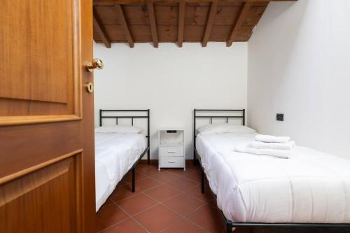 two beds in a room with white sheets at Dimora Oberdan 1800 - Duplex 70m from Arena 6 Beds in Verona