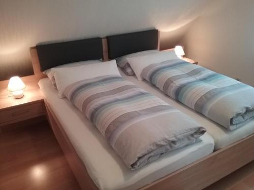 a bed with two pillows on it with two lamps at Haus Mühlgrund in Bad Wildbad