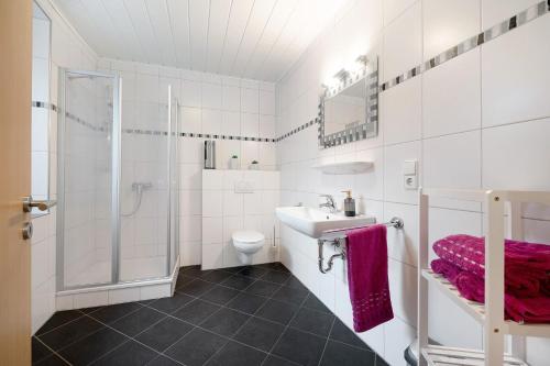 a white bathroom with a sink and a shower at Ferienwohnung Andres in Briedern
