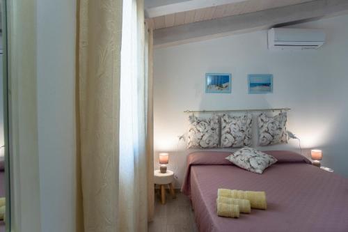 a bedroom with a pink bed with two yellow towels on it at Prima Luce in SantʼAnna Arresi