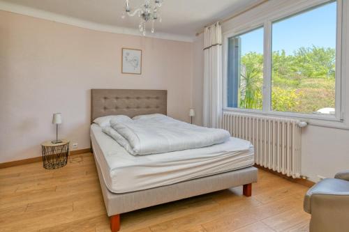 a bedroom with a bed and a large window at Maison Ker Hélène sur grand jardin in Guérande