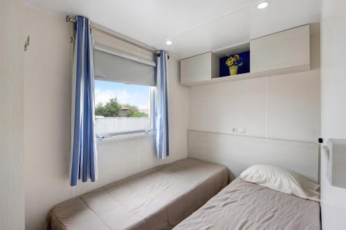 a bedroom with two beds and a window with blue curtains at Villa Granja Sol 2 in São Félix da Marinha