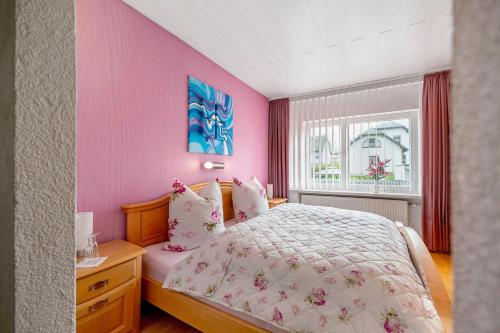een slaapkamer met een bed, roze muren en een raam bij Bellevie in Kell