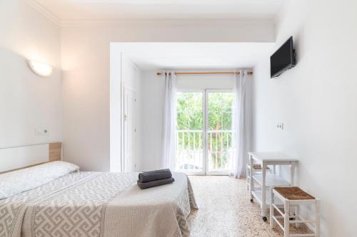 a white bedroom with a bed and a window at Hostal Moya in Roquetas de Mar