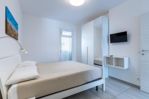 a white bedroom with a bed and a tv at Villa Vani - Appartamento 2 in Marina di Ragusa