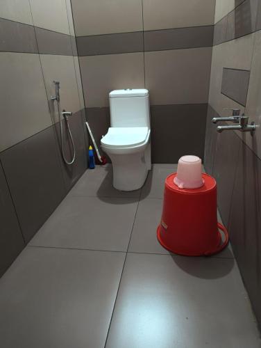 a bathroom with a toilet and a red stool at Alhind Residency , Valara, Munnar in Munnar