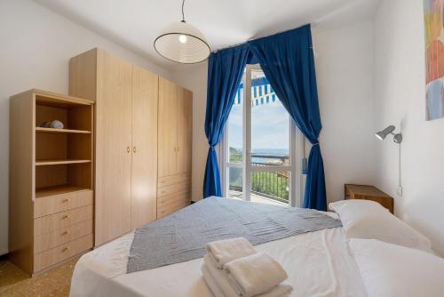 a bedroom with a bed with blue curtains and a window at Ca Giannina in Bonassola