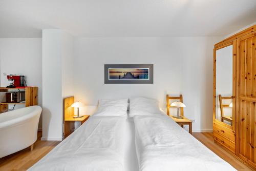 a large white bed in a room with two lamps at Ferienapartment Remke in Starnberg