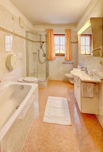 a bathroom with a tub and a toilet and a sink at Alpenhof Lodge Hirzer in Saltusio