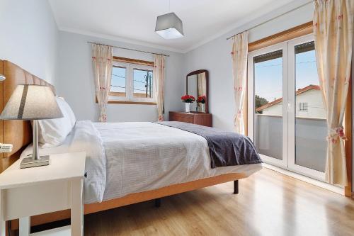 a white bedroom with a bed and a window at Vivenda Sol e Mar in Gafanha da Nazaré