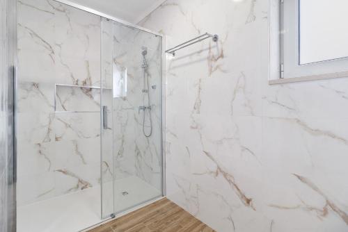 a bathroom with a shower with white marble walls at Vivenda Sol e Mar in Gafanha da Nazaré