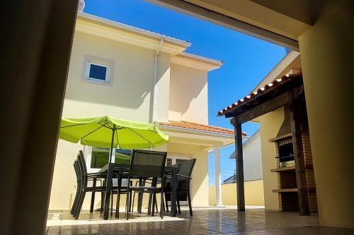 a table and chairs with a green umbrella on a patio at Vivenda Sol e Mar in Gafanha da Nazaré