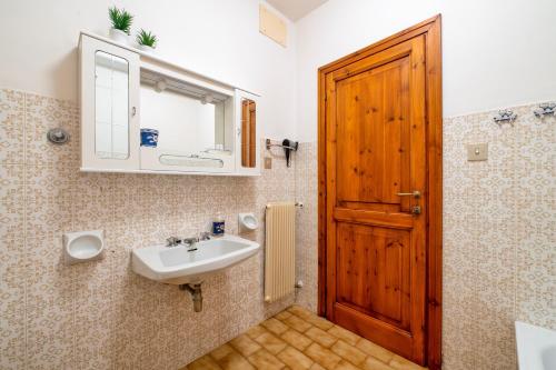 a bathroom with a sink and a wooden door at Appartamento Villa Marta in Spoleto