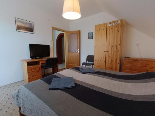 a bedroom with a bed and a desk and a television at Herőke Vendégház in Terény