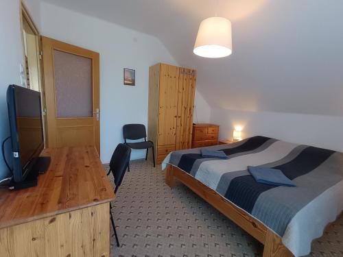 a bedroom with a bed and a desk and a television at Herőke Vendégház in Terény