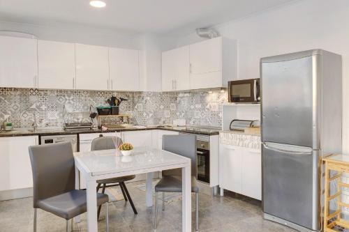 a kitchen with white cabinets and a table and a refrigerator at Funchal House in Funchal