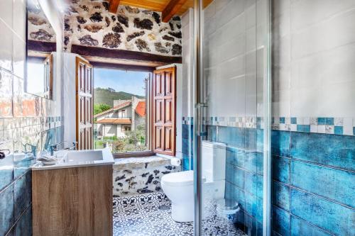 a bathroom with a toilet and a sink and a window at Casa Trasmiera in Solórzano