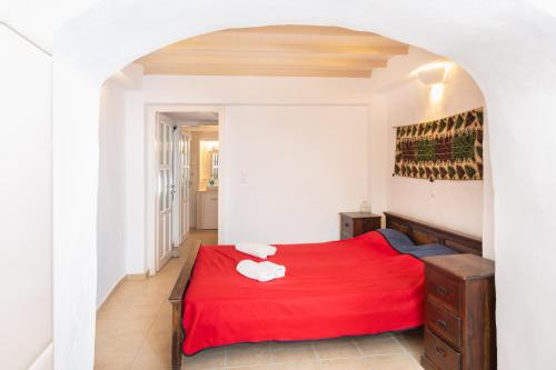 a bedroom with a red bed with a red blanket at Karai traditional house in Astypalaia