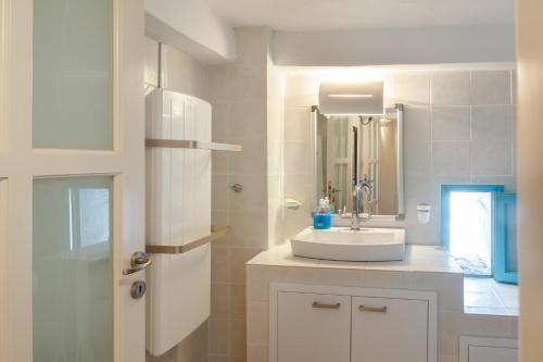 a white bathroom with a sink and a mirror at Karai traditional house in Astypalaia