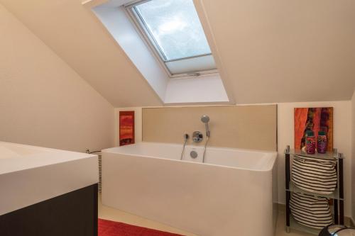 a bathroom with a large white bath tub with a skylight at Dachatelier Überlingen in Überlingen