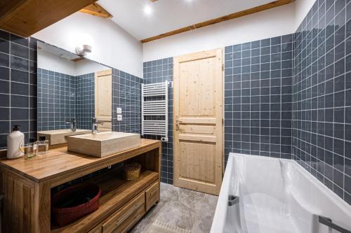 a bathroom with blue tiles and a tub and a sink at Chalet Marmotte in Saint-Martin-de-Belleville