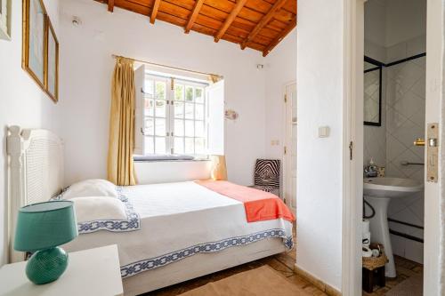 a bedroom with a bed and a sink and a window at Casa Da Guia in Beja