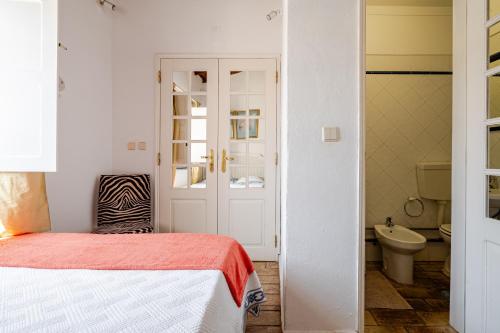 a bedroom with a bed and a bathroom with a toilet at Casa Da Guia in Beja