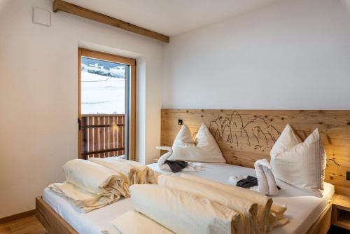 a bedroom with two beds and a window at Planerhof Apartment Enzian in Funes